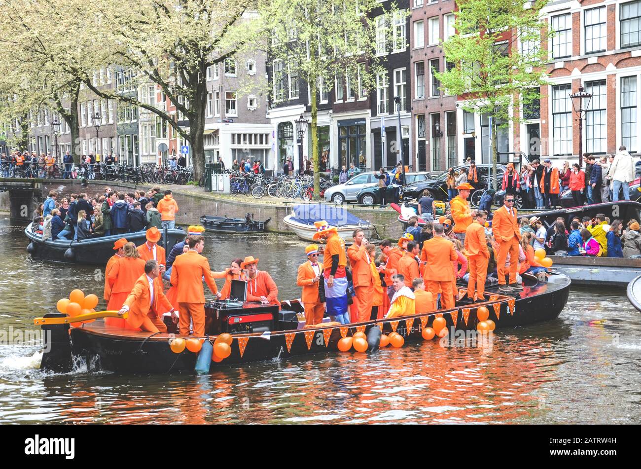 Amsterdam, Netherlands - April 27, 2019: People on party boats dressed in national orange color while celebrating the Kings day, Koningsdag, the birthday of the Dutch King Willem-Alexander. Stock Photo