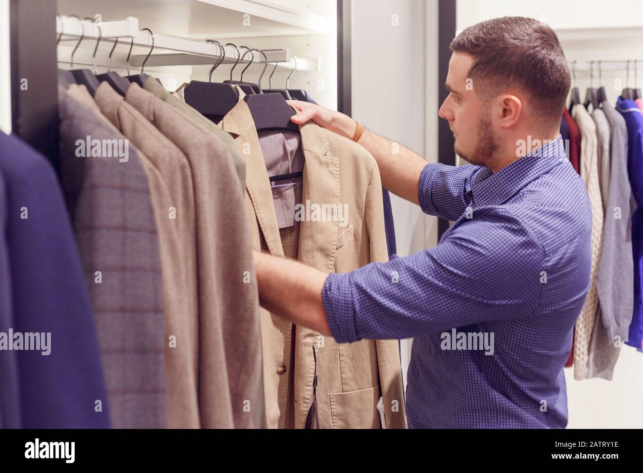 Man chooses a classic coat in a clothing store, a fashion boutique. Stock Photo