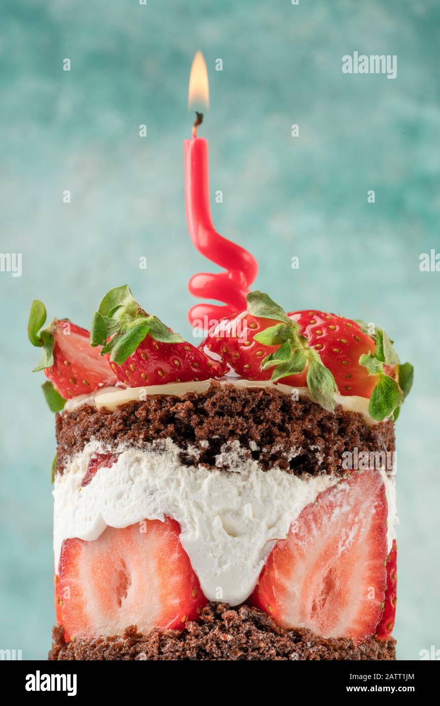 a birthday cake decorated with strawberry has one candle on it Stock Photo