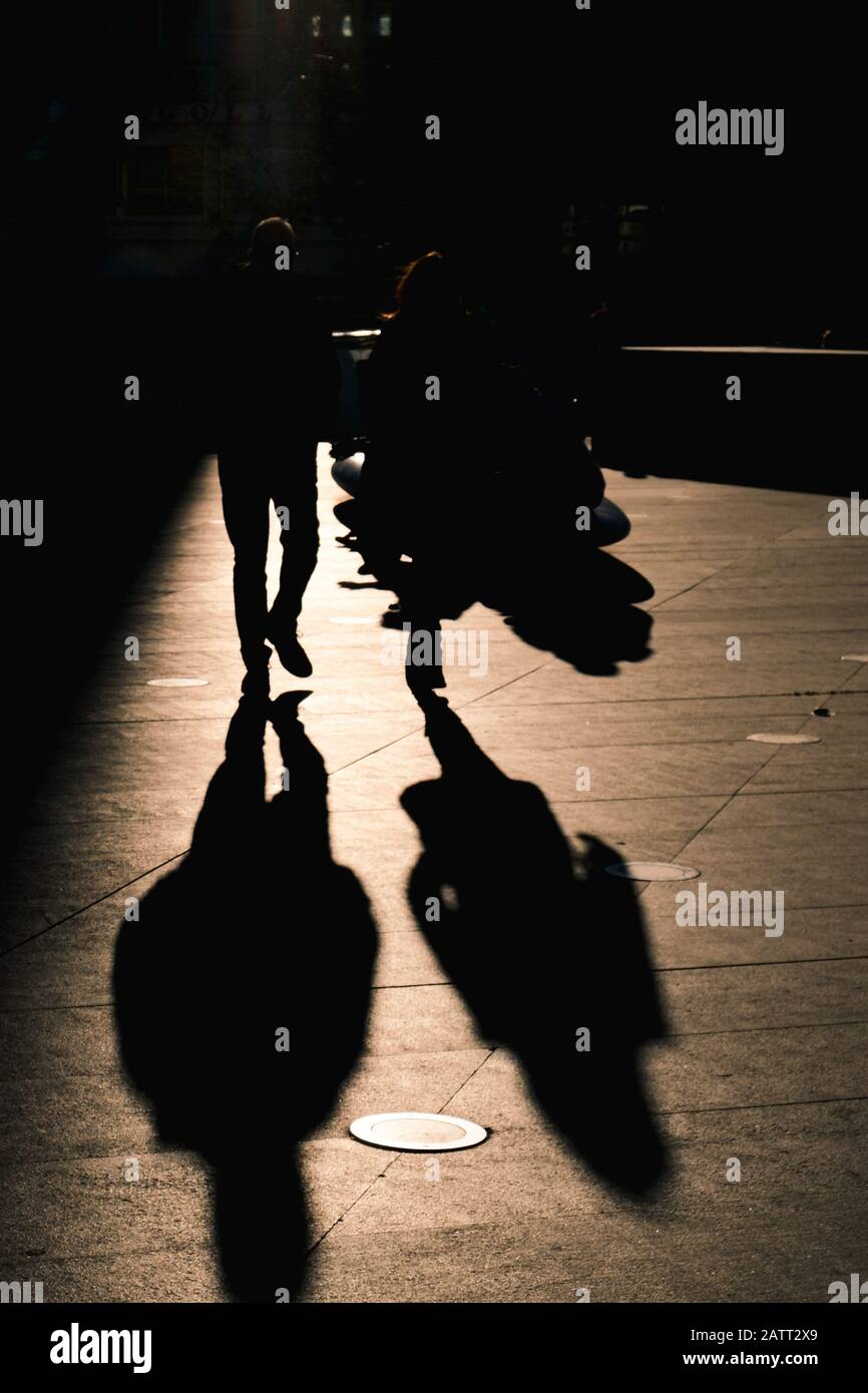 Unrecognized people walking with sunlight on the back creating strong shadows and silhouettes Stock Photo