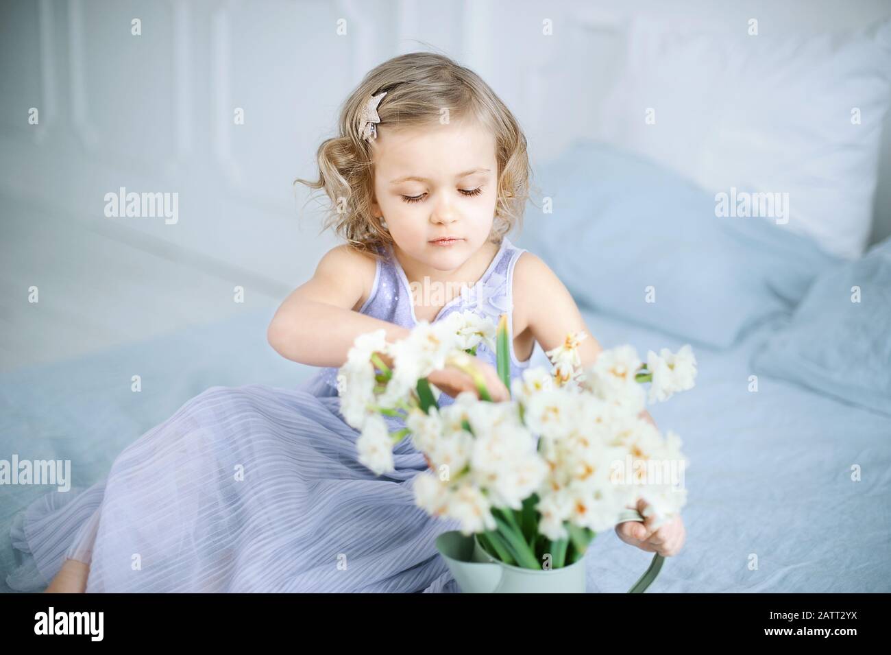 girl holding narcissus in hands. Adorable smiling little girl holding flowers for her mom on mother's day Stock Photo