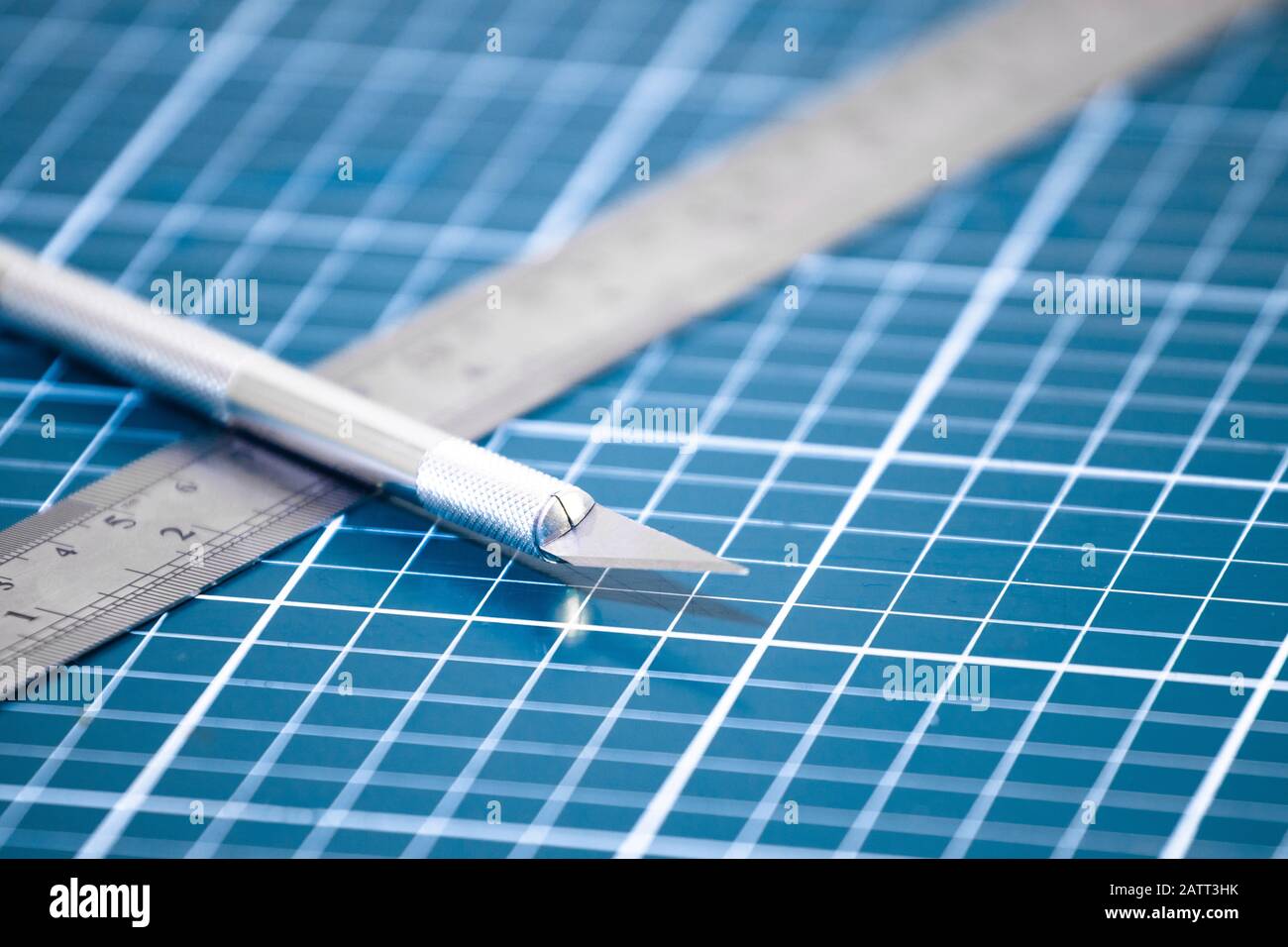 Stationary equipments on blue cutting mat. Metal ruler and scalpel ...