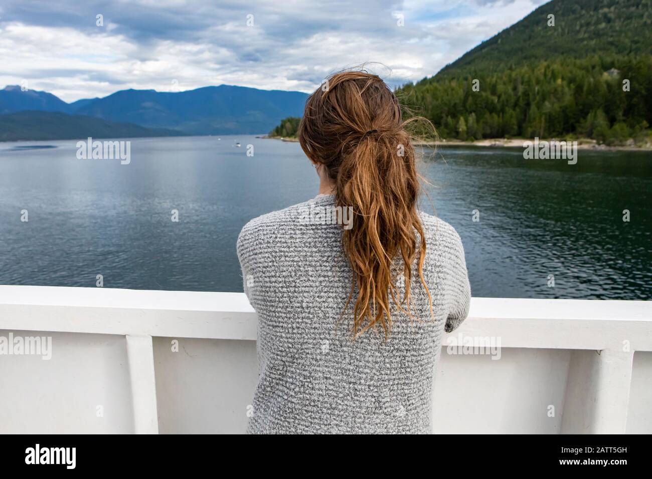 Close up shot from behind of a female passenger of a ferryboat navigating  in a canadian lake. Passenger looking at landscape near the deck's railing  Stock Photo - Alamy