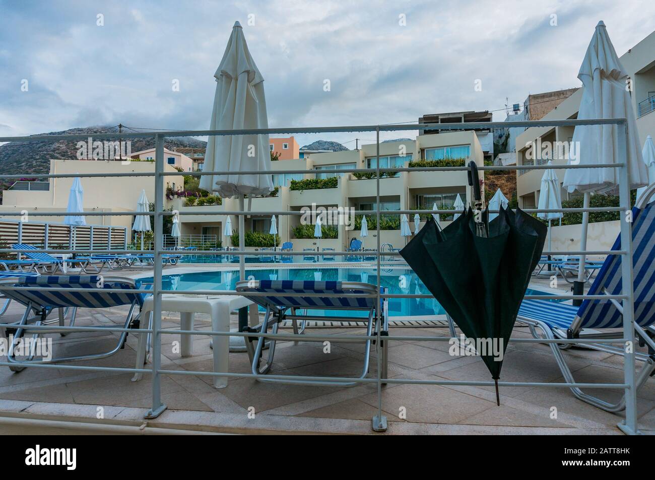 Bali, Crete, Greece - 08.10.2019: after the rain by the pool in the resort. Folded beach umbrellas and a large black umbrella. Stock Photo