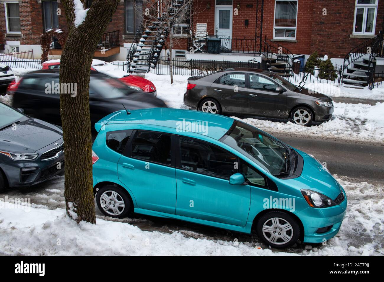 January 26, 2020 - Rosemont, Montreal, Quebec, Canada: Turquoise car and cars parked along sideways on a residential street during day winter Stock Photo