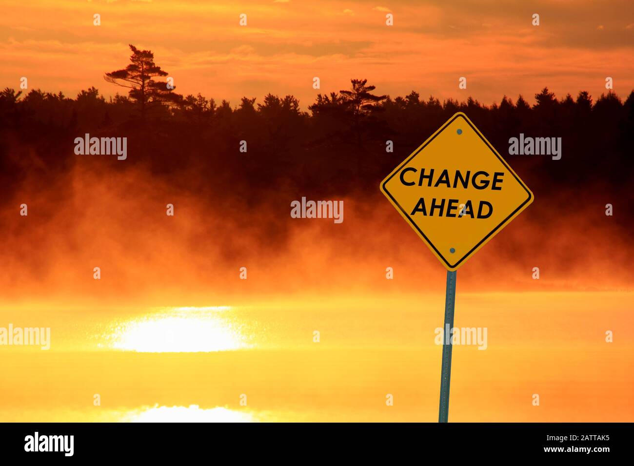 a caution sign beside a lake at sunrise that says CHANGE AHEAD Stock Photo