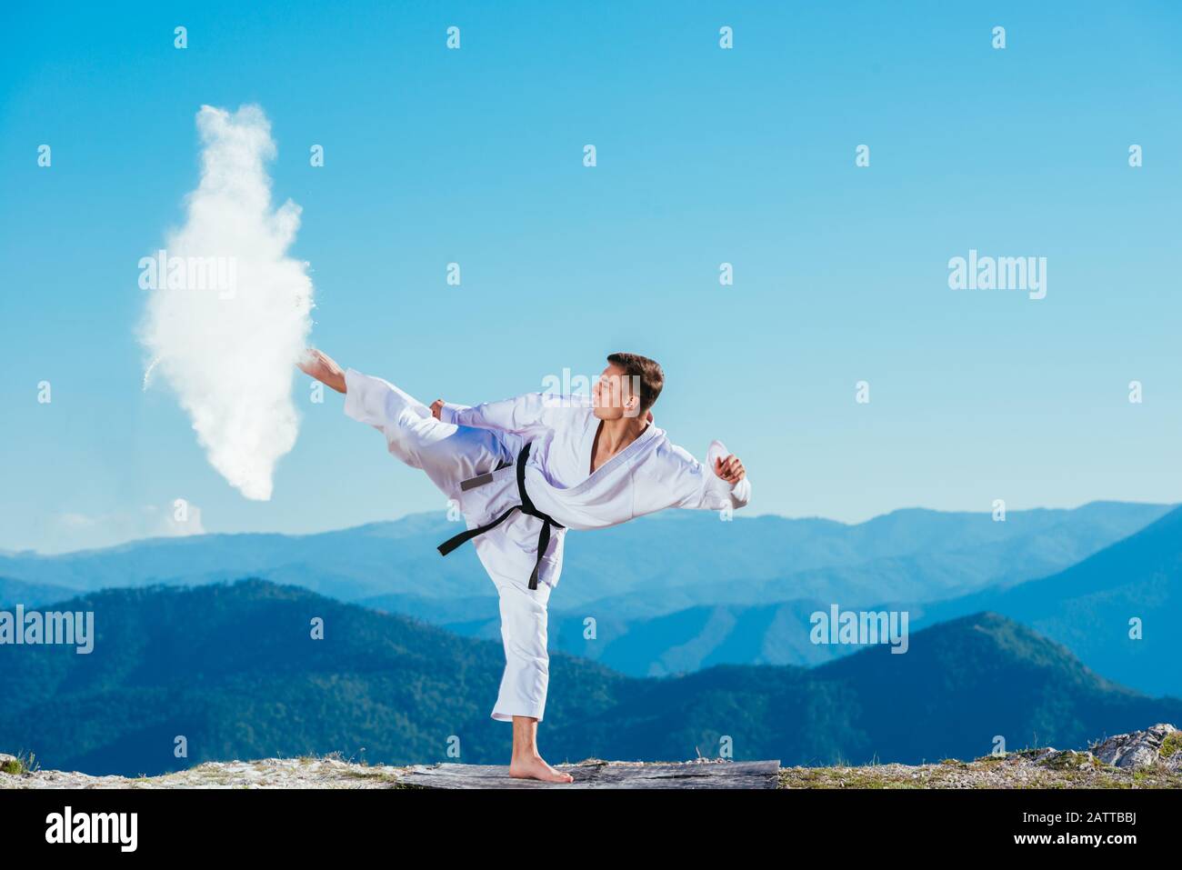 Fit karate athlete kicking a cup filled whit fluor causing a big splash ...