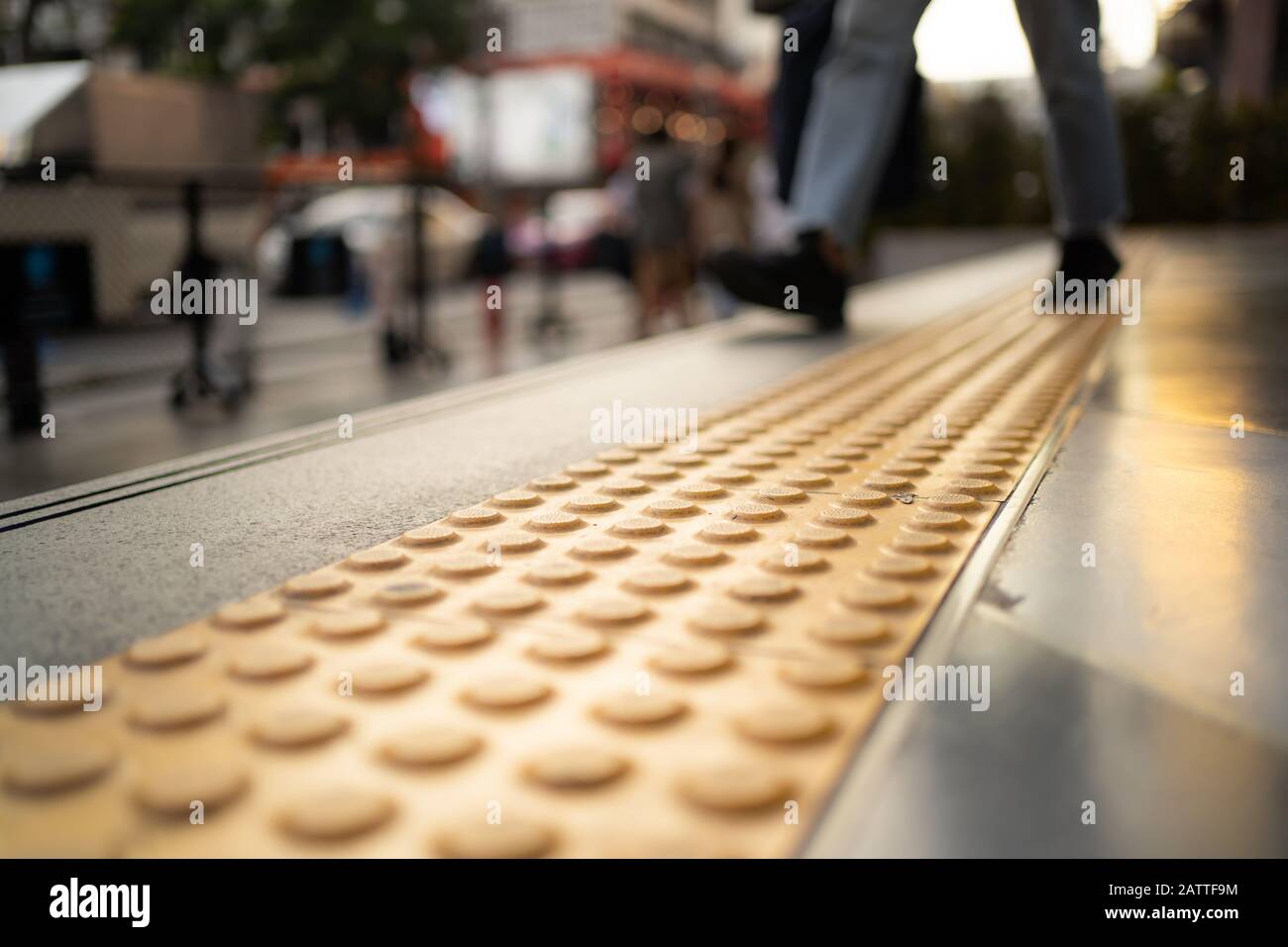 Pedestrian walking on tactile paving on footpath Stock Photo