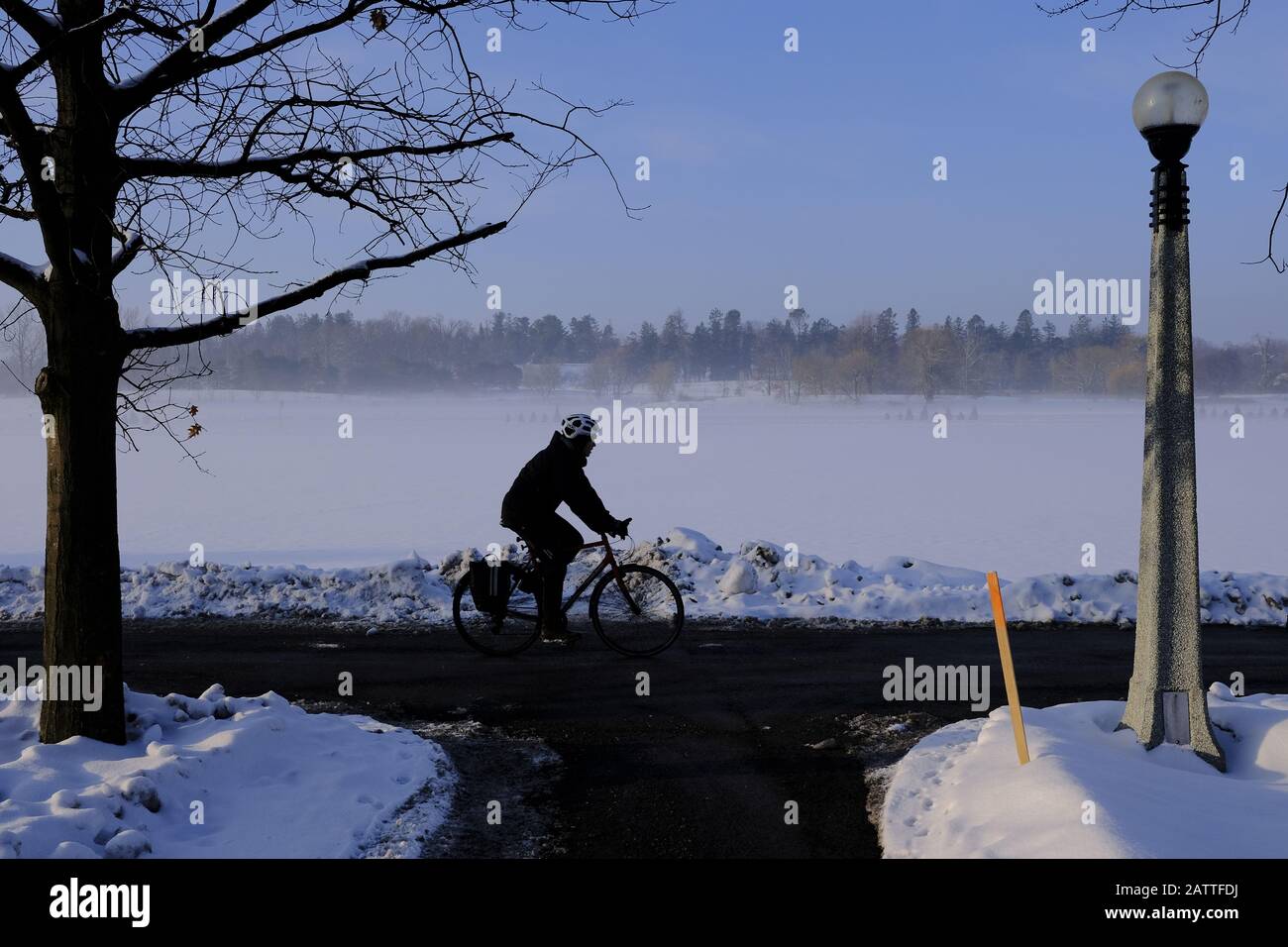 Winter cyclist riding along the Rideau Canal Western Pathway by Dow's Lake on a very cold February morning. Ottawa, Ontario, Canada. Stock Photo