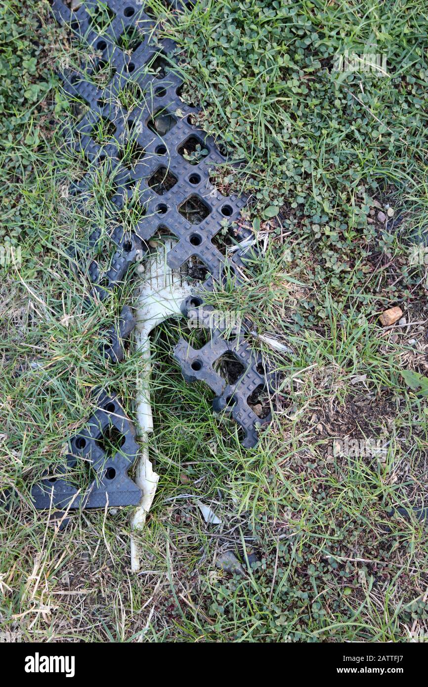 A section of black damaged erosion control matting in a park showing where a damaged and broken drain has collapsed caused the matting to break. Stock Photo