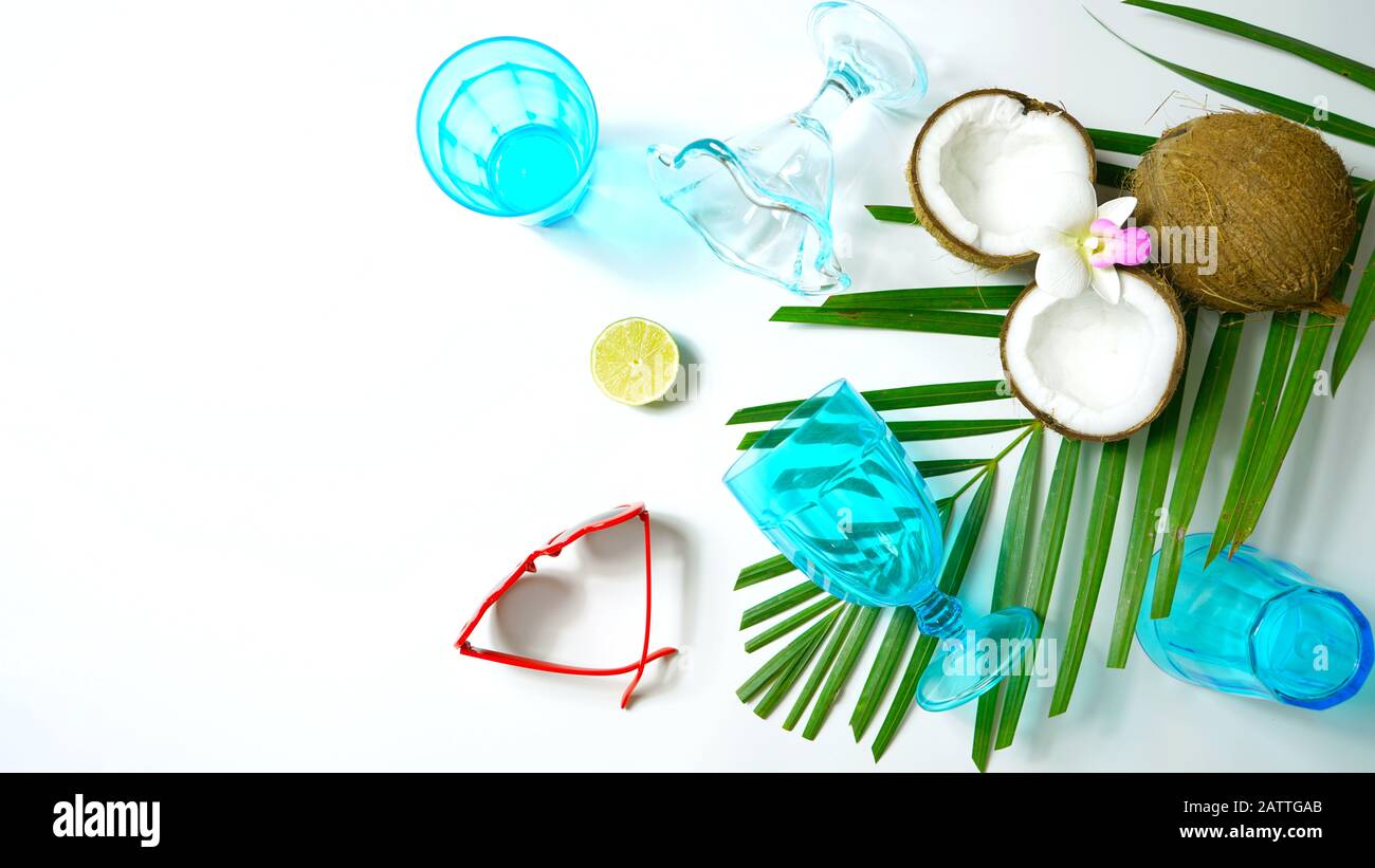 Coconut summertime entertaining theme flat lay creative layout overhead with shadows from blue drinking glasses cast over table. Stock Photo