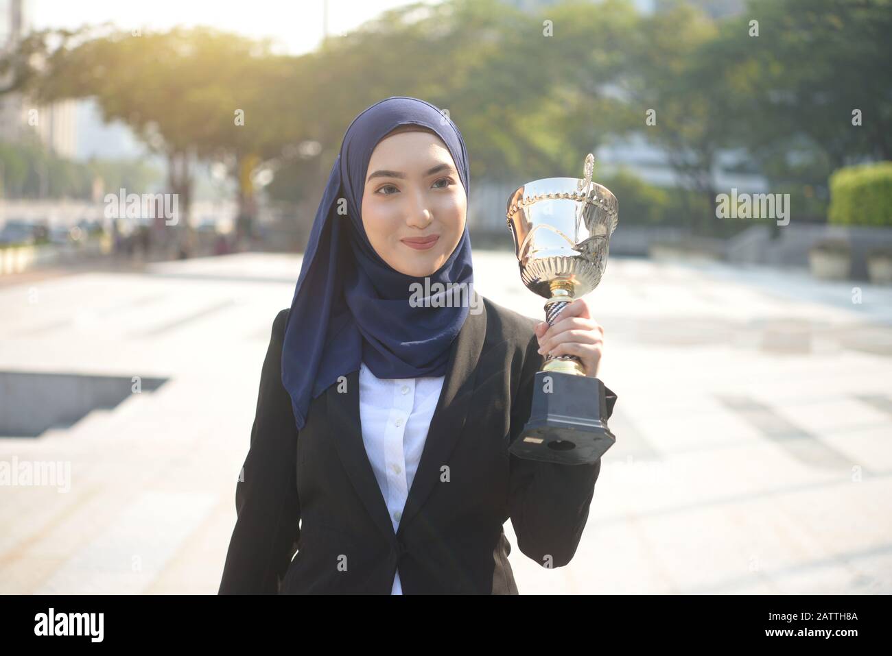 Young asian muslim woman in head scarf smile holding trophy symbol of success Stock Photo
