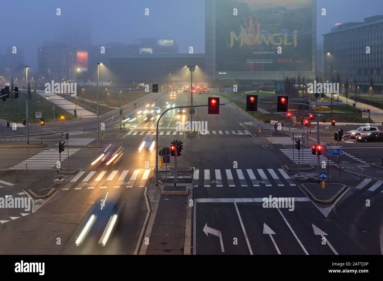 Via Melchiorre Gioia in the evening fog with traffic lights and moving cars, seen from the suspended pedestrian walkway of Piazza Alvar Aalto, Milan Stock Photo