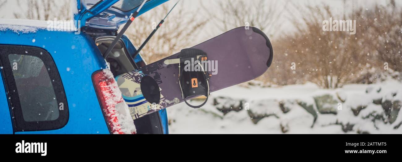 The snowboard does not fit into the car. A snowboarder is trying to