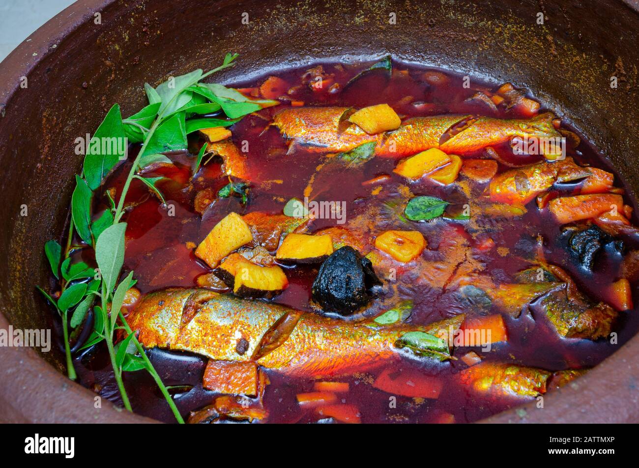Cooked Sardines Curry with coconut garnished with curry leaves in a clay pot ready to be served. Stock Photo