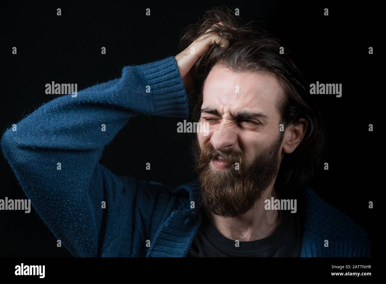 Young man with long hair with hippie type long beard, surprised face, in black isolated background. Hipster Concept. Stock Photo