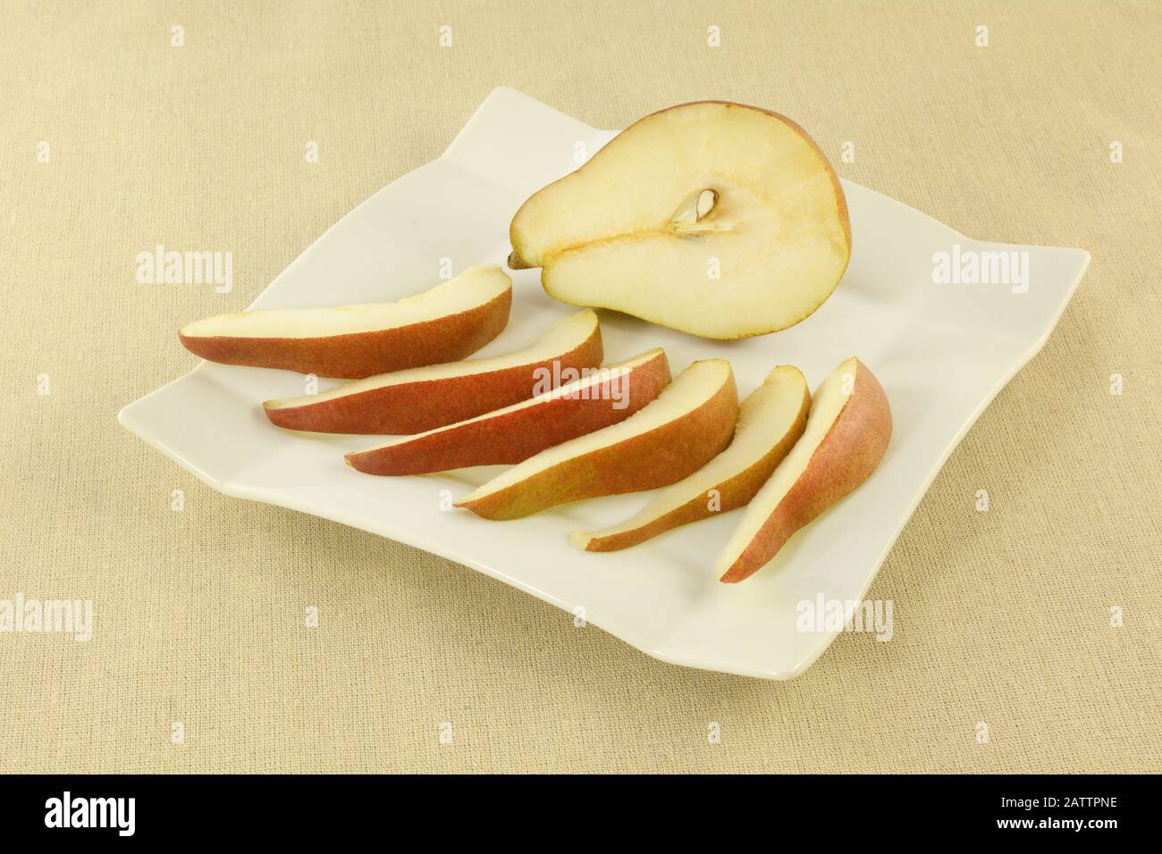 Fresh raw red anjou pear slices and half on white plate Stock Photo