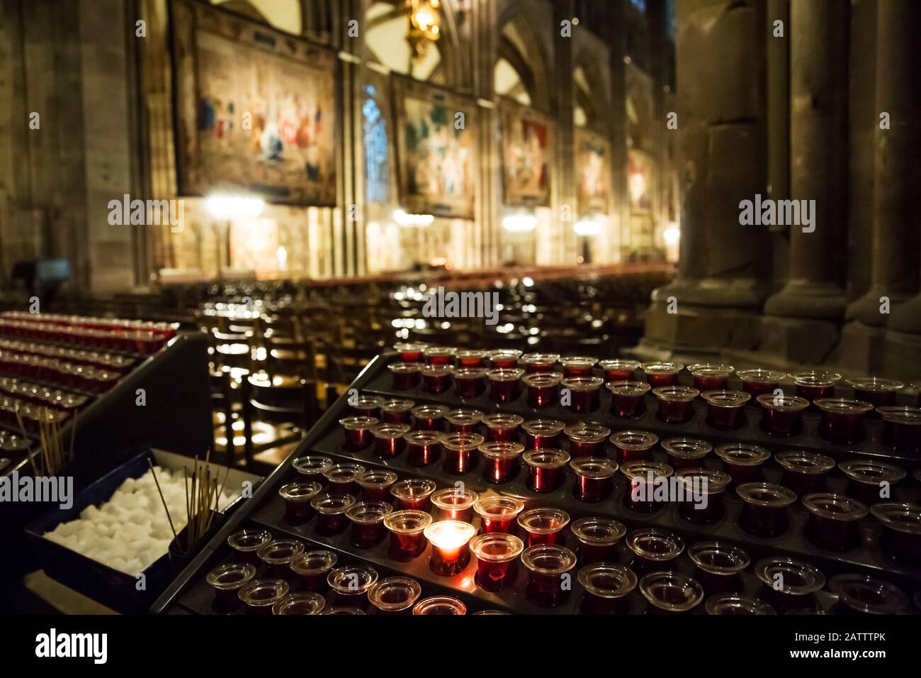 Lighting candles in a catholic temple . Candles are lit near the altar