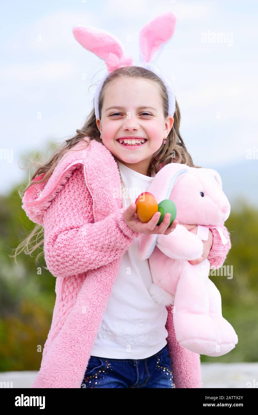 Happy girl holding pink rabbit toy and eggs. Child smiling with bunny ...