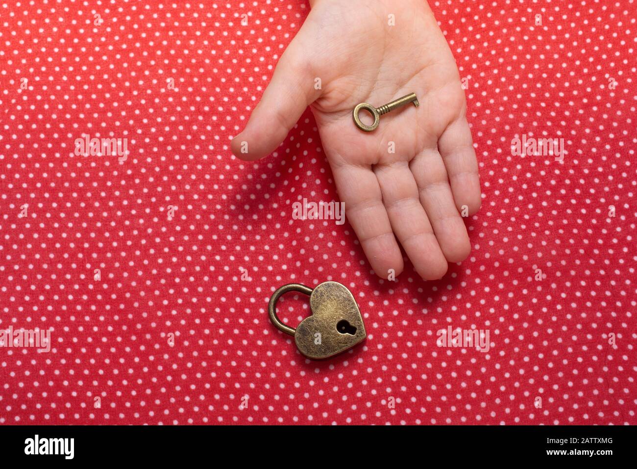 Hand holding a heart shaped lock and key on a red background Stock ...