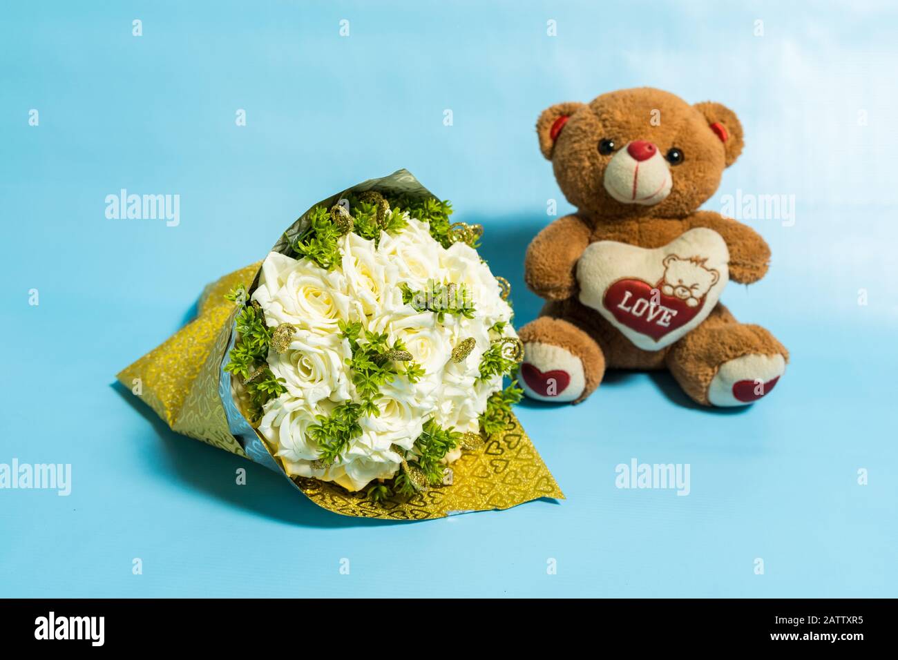 Teddy bear holding bouquet of red roses valentines day Stock Photo - Alamy