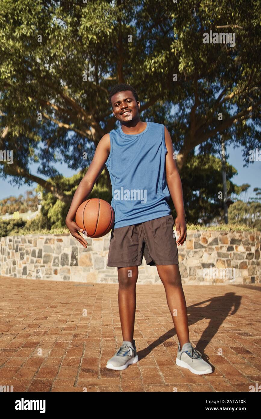 Active smiling portrait of a basketball player standing in front of