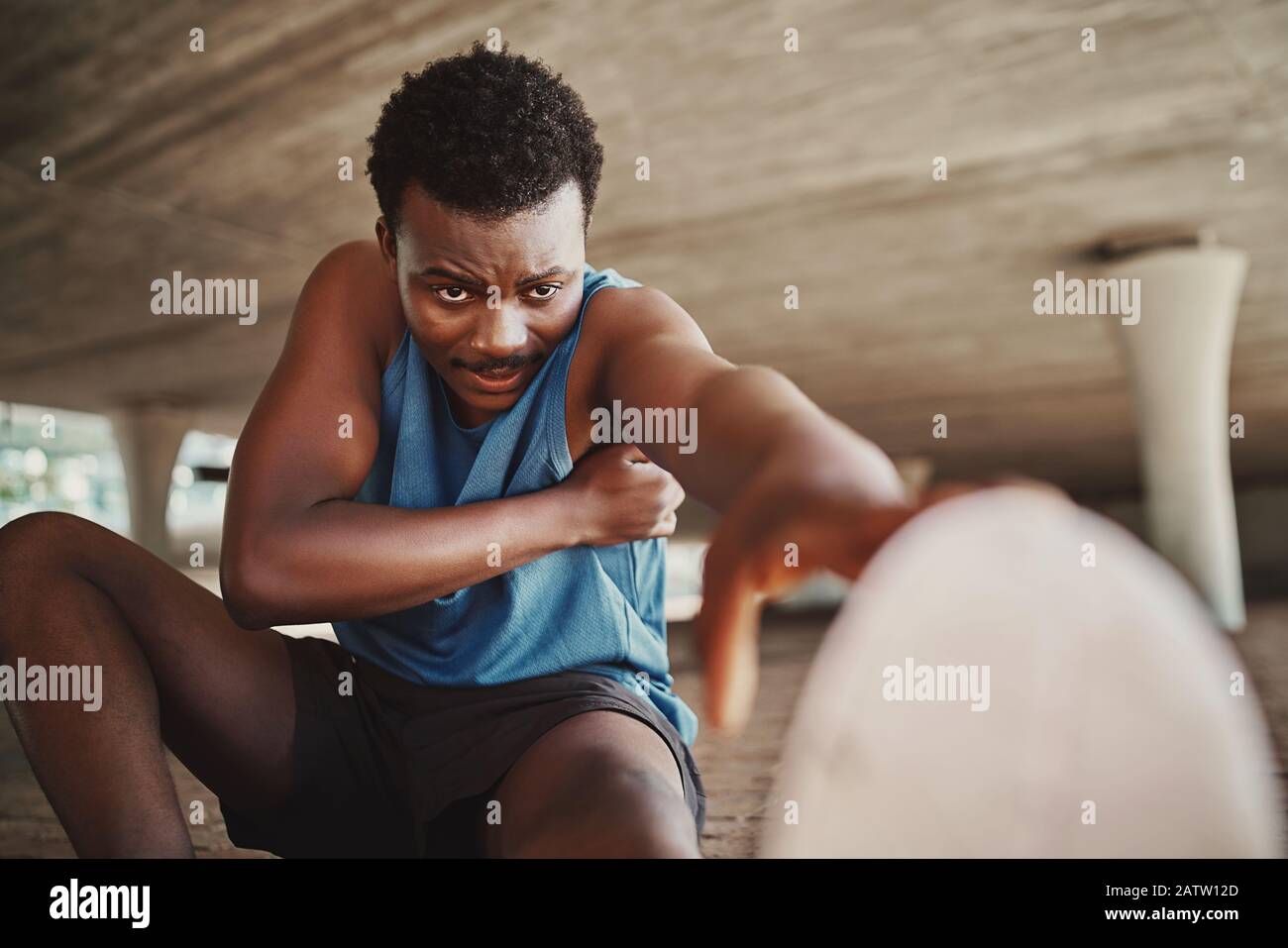 Portrait of a male runner trying hard to stretch his legs before running outdoors Stock Photo
