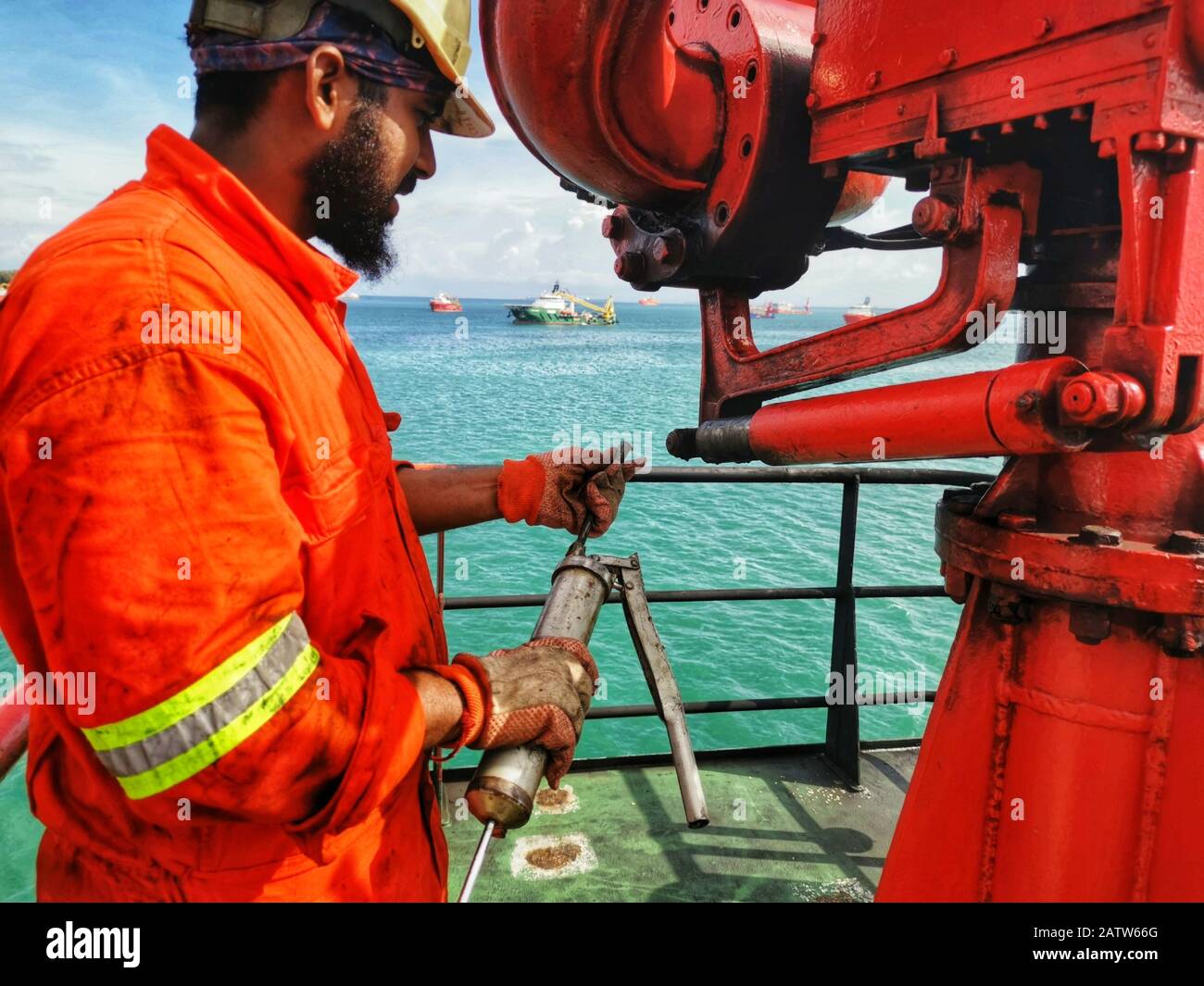 Offshore marine crew doing schedule serviced maintenance and grease at FIFI firefighting monitor on boards ship Stock Photo