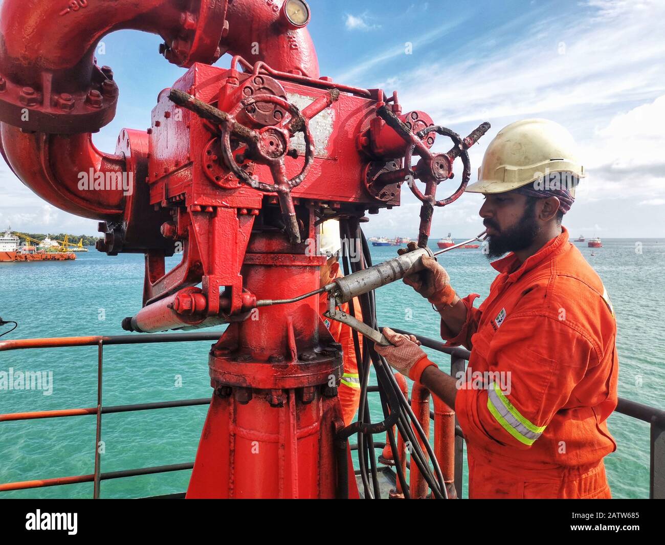 Offshore marine crew doing schedule serviced maintenance and grease at FIFI firefighting monitor on boards ship Stock Photo