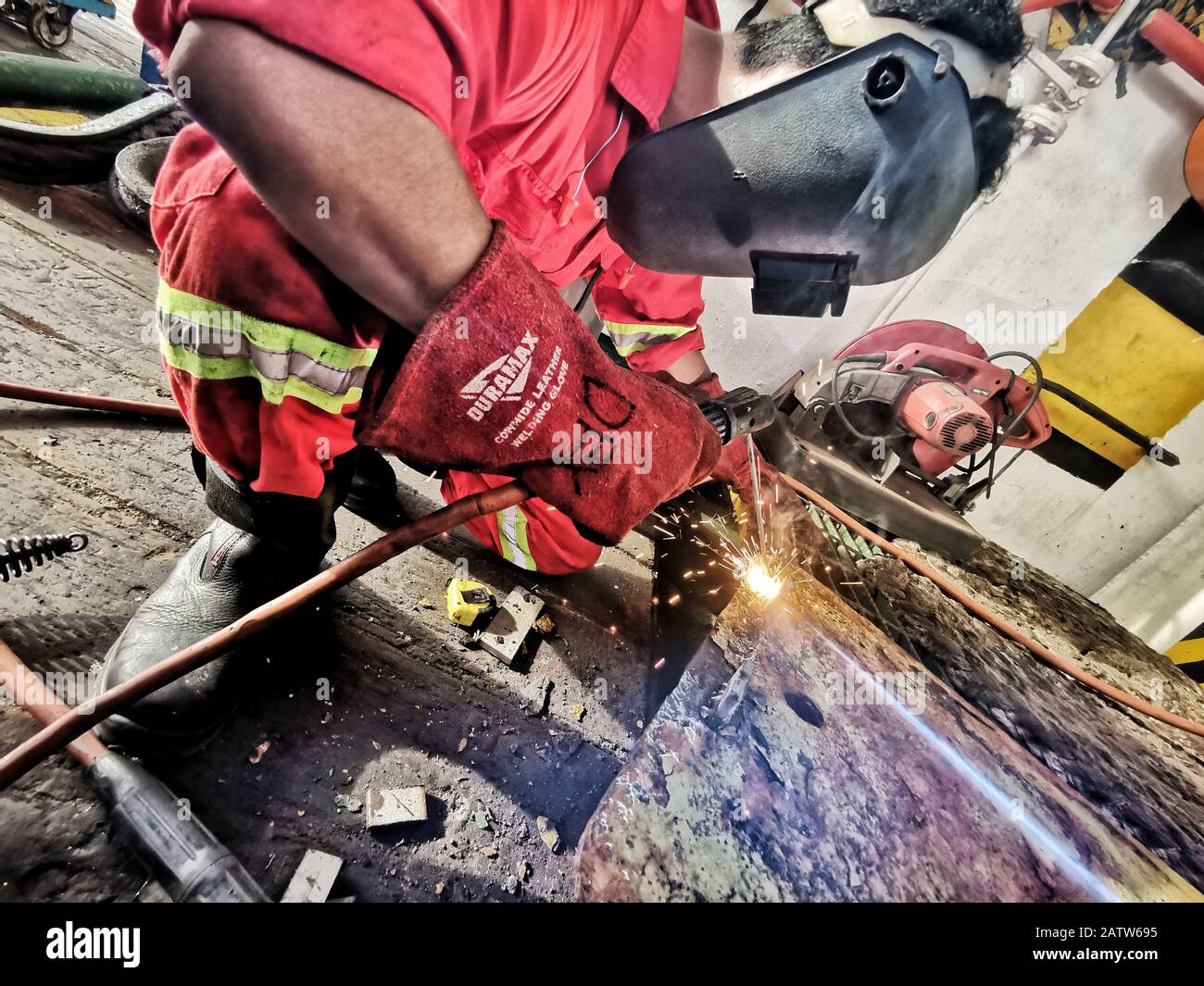 marine crew welding iron plate wearing full PPE Stock Photo