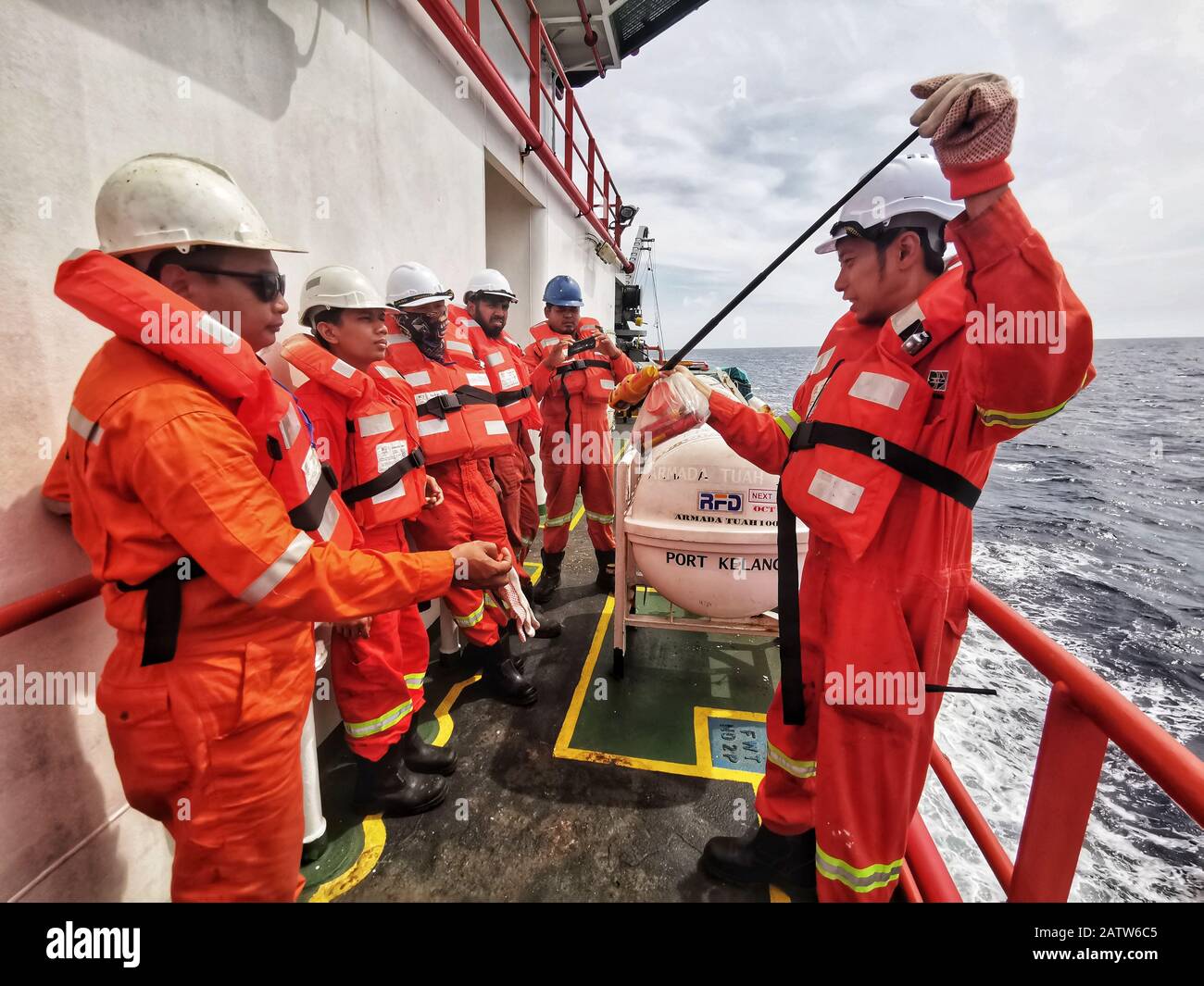 chief officer doing short briefing using safety equipment  and pyrotechnic during abandon ship drill Stock Photo