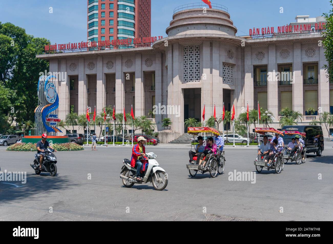 Hanoi, Vietnam - August 22, 2017: Scooter traffic in front of State Bank of Vietnam with APEC banner in front of the building in Hanoi Stock Photo