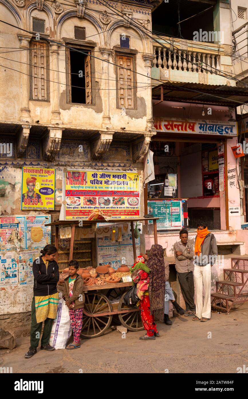 India, Rajasthan, Shekhawati, Ramgarh, main street, customers at pottery, stall outside old street corner haveli Stock Photo