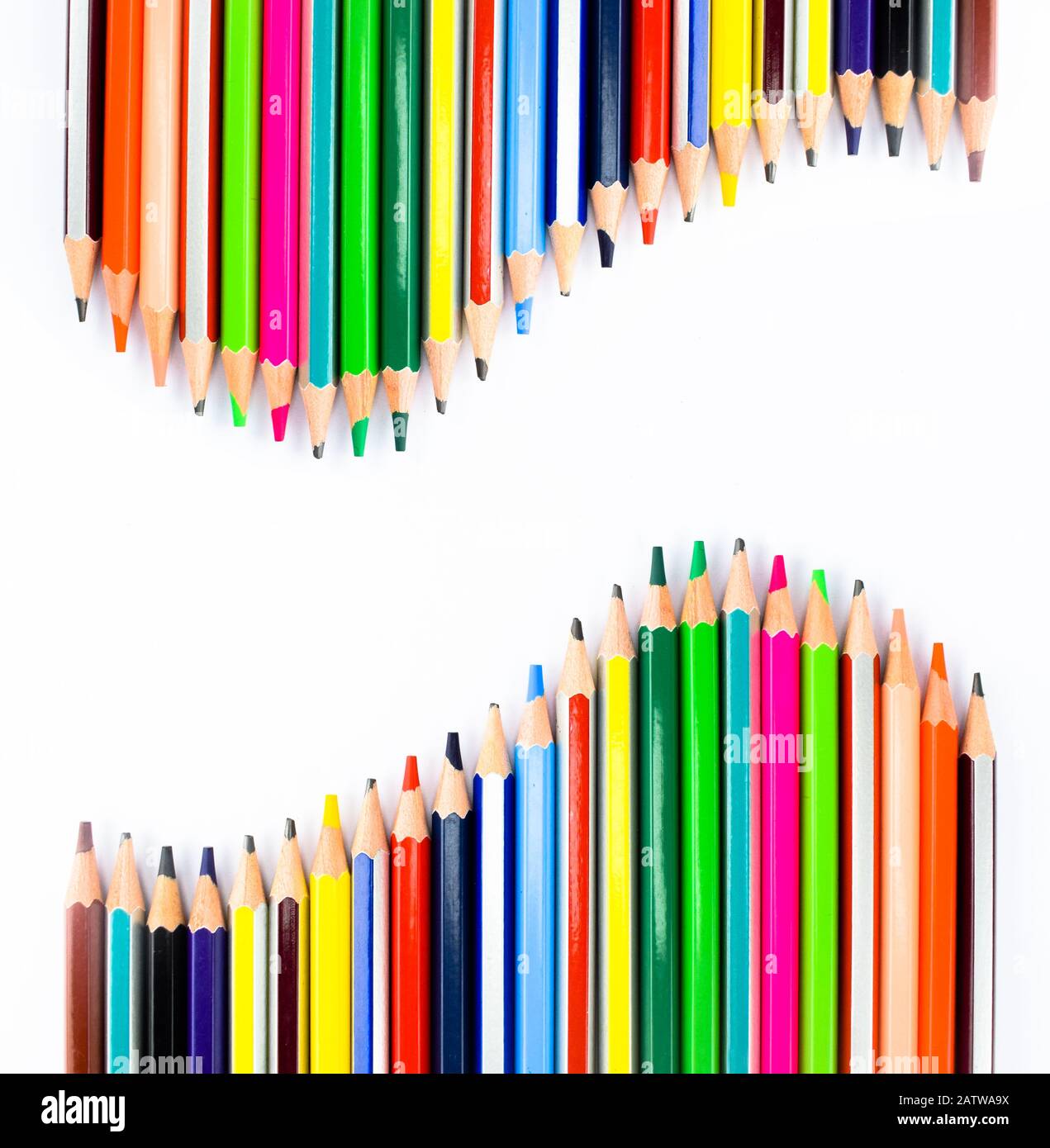 Two similar row of different colored pencil crayons arranged facing each-other on a white background Stock Photo