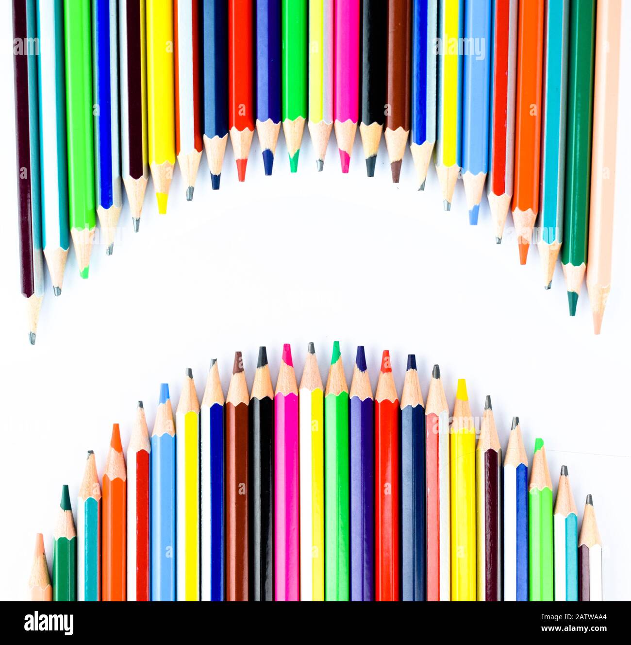 Two waved row of different colored pencil crayons making a white blank space to write different text in it Stock Photo