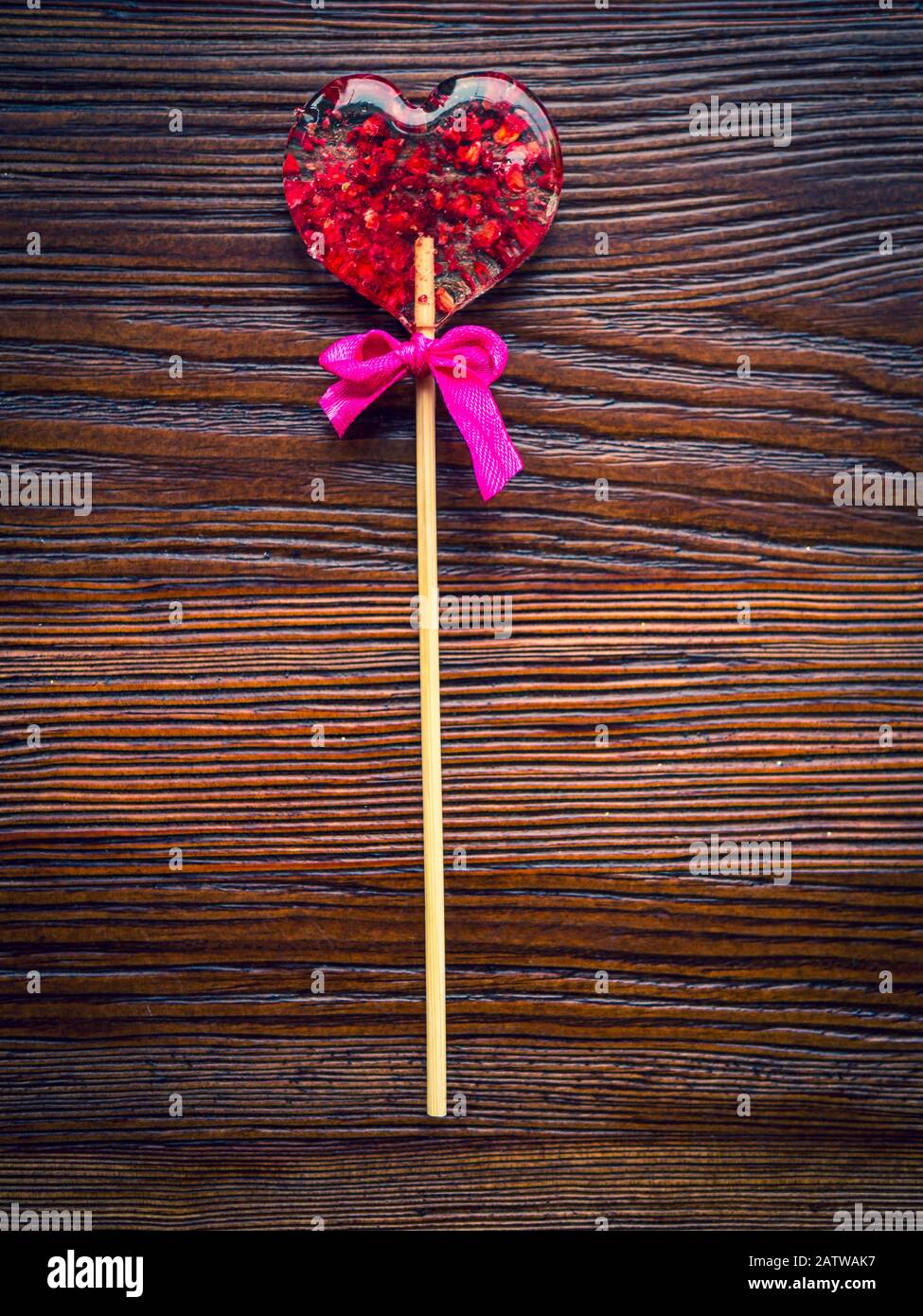 Red heart-shaped candy. Valentines day greeting card. Handmaded candy heart with strawberries and cranberries, on wooden table. Top view with copy Stock Photo