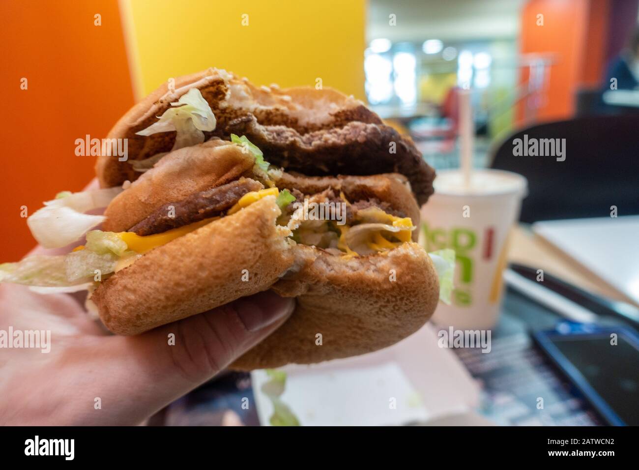 A person eating a Big Mac hamburger in a McDonalds fast food restaurant. Stock Photo