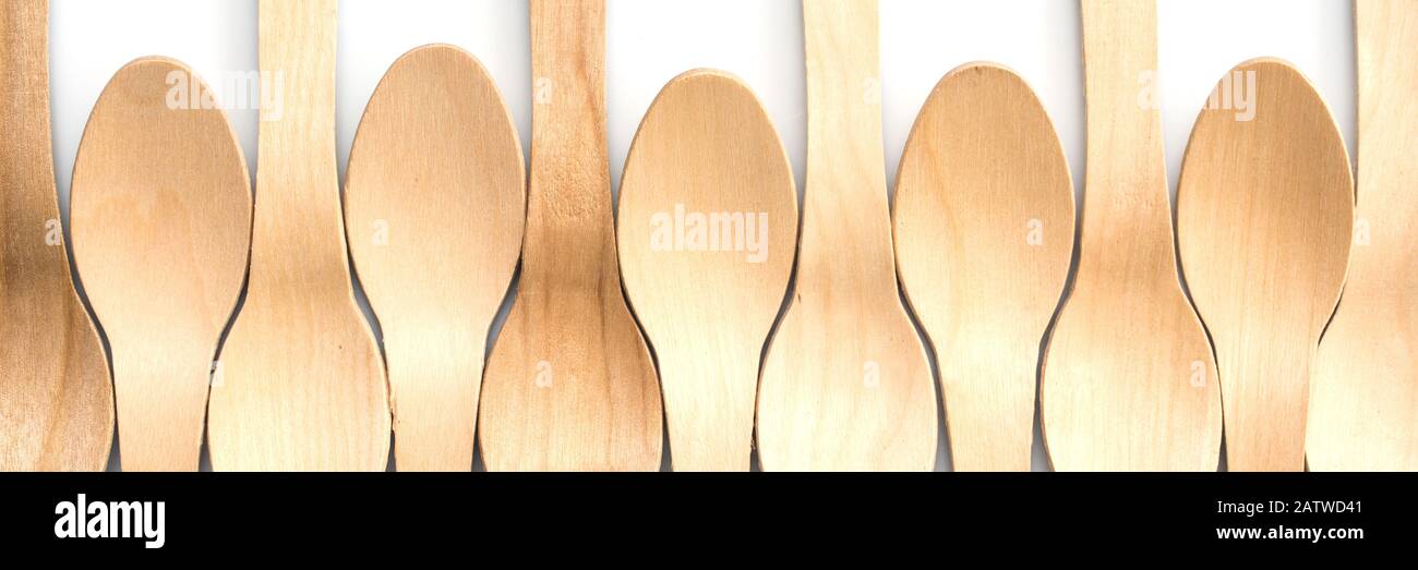 Wooden spoons aligned on white panoramic background, plastic free, environment friendly disposable cutlery web banner Stock Photo