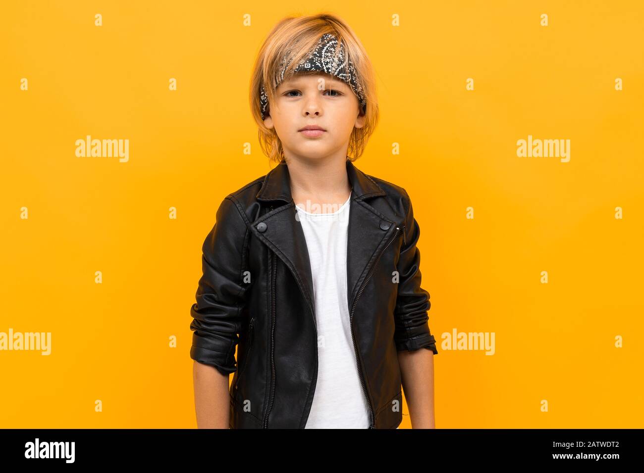 European blond boy in a black leather jacket and white T-shirt with a  bandana on a yellow background Stock Photo - Alamy