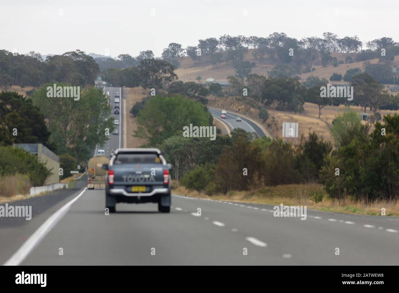 cars driving on a big dip on a freeway through the australian bush on the hume highway Stock Photo