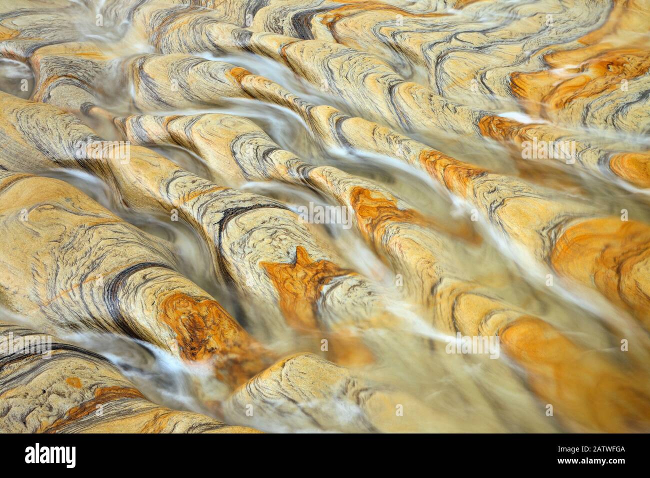 Water flowing over weathered rock with natural patterns, Northumberland ...
