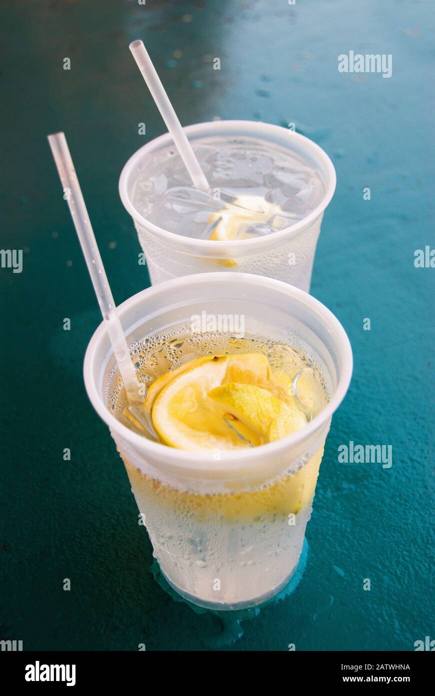 https://c8.alamy.com/comp/2ATWHNA/two-transparent-plastic-cups-filled-with-ice-cold-water-and-lemon-slices-shot-at-an-outdoor-restaurant-2ATWHNA.jpg