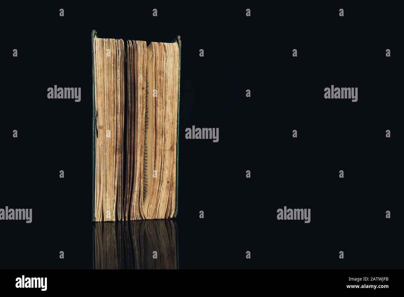 Ancient book shot on black background. The book is in bad condition ...