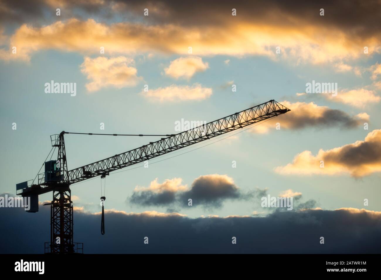 construction crane silhouette in a building under construction with a cloudy sky background at dawn Stock Photo