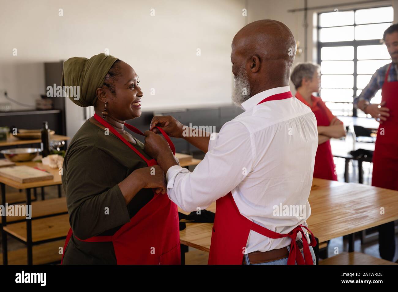 African man helping an African woman to put on her apron Stock Photo