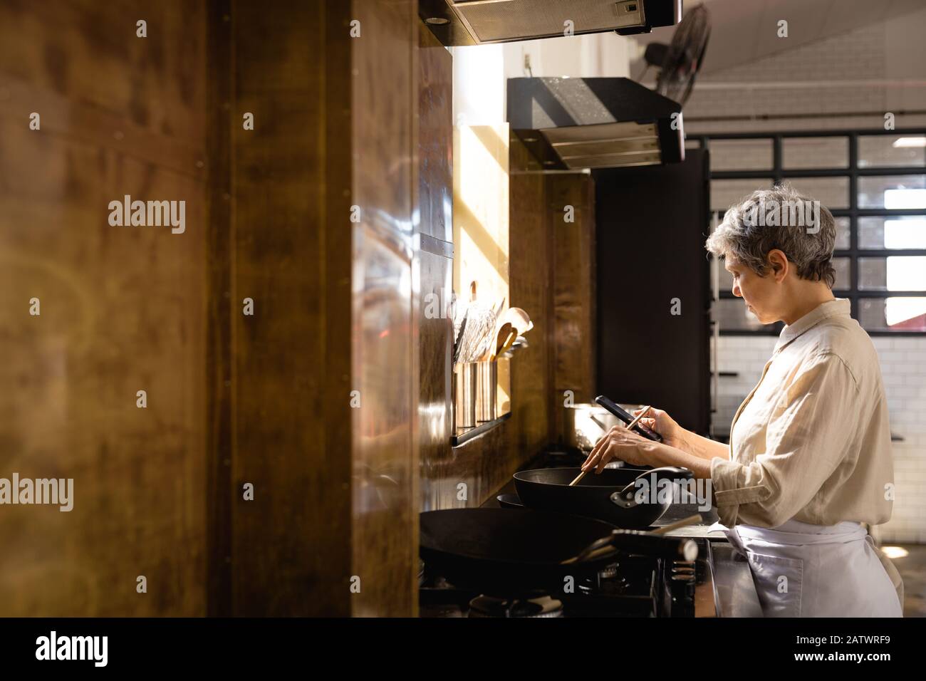 Caucasian chef cooking with her smartphone Stock Photo