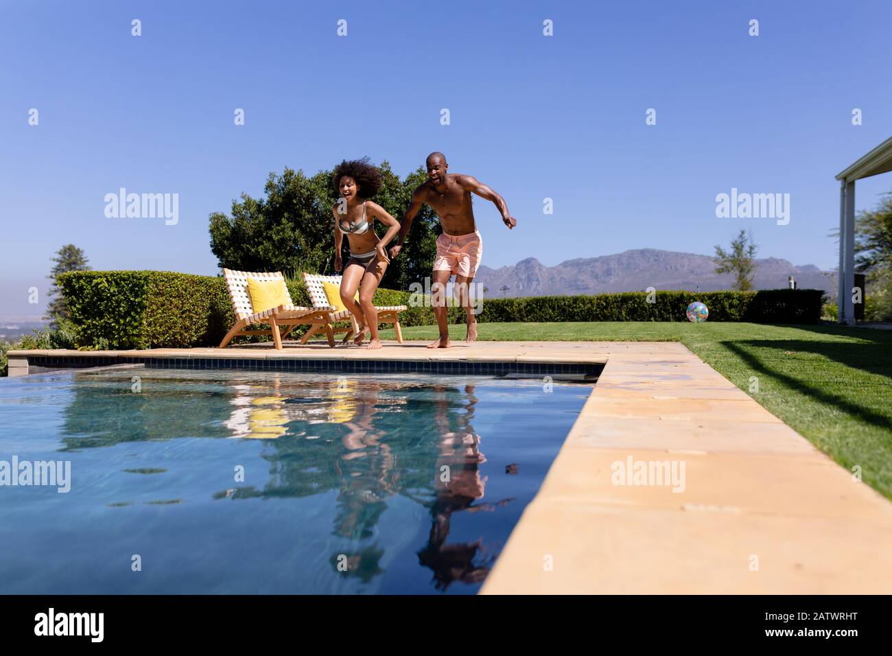 Young couple jumping on swimming pool on a sunny day Stock Photo