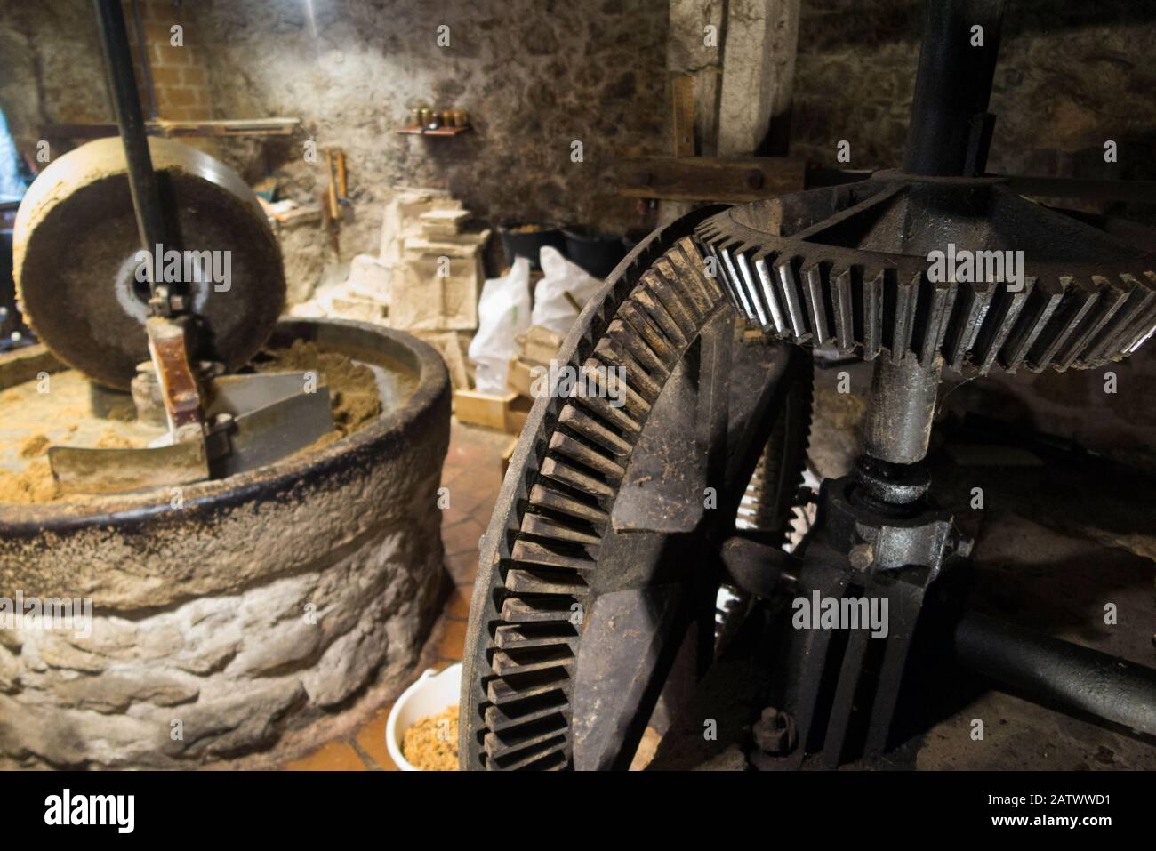 Metal wheels with cogs and teeth at the Le Moulin de Chanaz where milling grinding of the walnuts with round stone water powered mill grind wheel prior to pressing them / compressing to extract the Walnut oil takes place, at a watermill in France Stock Photo