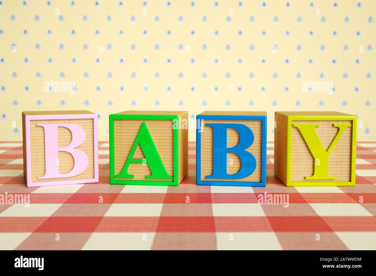 Childrens wooden ABC blocks spelling BABY on a checked tablecloth Stock Photo