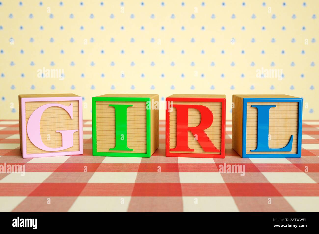 Childrens wooden ABC blocks spelling GIRL on a checked tablecloth Stock Photo